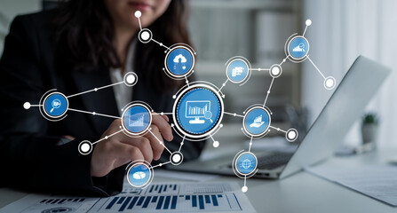 A businesswoman interacts with her laptop in a modern office, surrounded by digital icons representing network connectivity and data analysis, highlighting technology role in business success. Crux