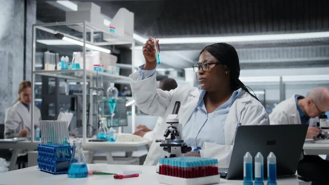 Lab materials scientist investigating blue liquid polymer properties in test tube container. Researcher testing new synthetic material durability and viscosity in lab, camera A
