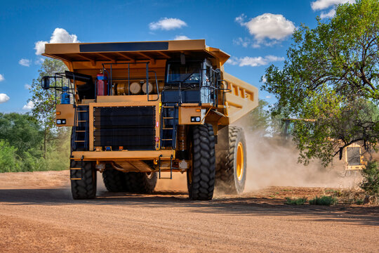 Huge Yellow Diamond Mining Dump Truck driving on Dusty Dirt Road, at an open pit diamond mine