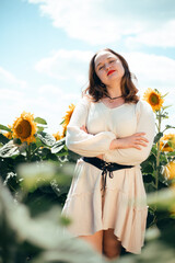 Sunflowers bloom in a field while a woman smiles in front of them on a sunny day during the summer season in a rural area