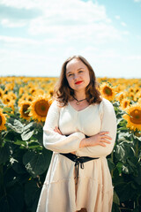 Sunflowers bloom in a field while a woman smiles in front of them on a sunny day during the summer season in a rural area