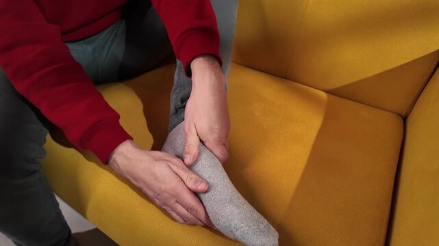Man at home holding painful injured foot.	

