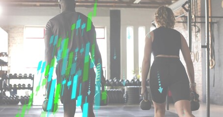 Holding kettlebells, training partners in gym gear walking in warehouse gym with rigs and overlays