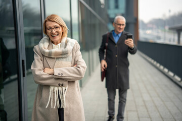 Mature woman smiling with crossed arms in city