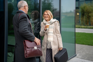 Senior business people talking outside modern office building