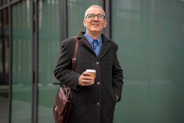 Senior man smiling holding coffee cup in city
