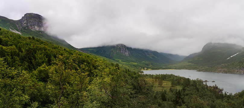 Innerdalen nature reserve shows the beautiful mountain valley with dramatic clouds overhead. Innerdalsvatna lake and the misty Trollheimen mountains range in Sunndal, M&oslash;re og Romsdal Norway.
