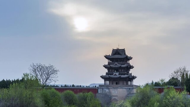 Time-lapse still of Qiu Feng Pavilion in Shanxi at cloudy dawn, traditional Chinese architecture framed by trees and soft morning light, China
