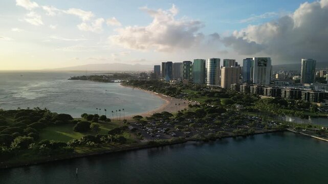 Drone aerial view of Waikiki Beach coastline and Honolulu skyline with ocean bay and golden hour light in Hawaii USA
