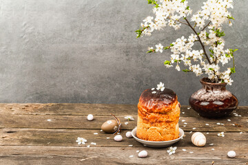 Traditional Easter cake in a rustic style. Vintage baking pot, blooming cherry plum branches. Wooden background