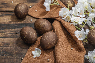 Easter eggs and blooming cherry branches on dark wooden background. Festive concept, greeting card