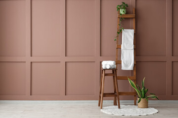 Stool and ladder with clean towels near brown wall in room © Pixel-Shot