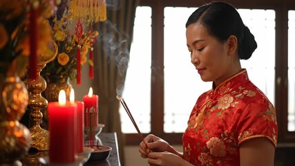Chinese Woman in Traditional Attire Offers Incense During Chinese New Year Celebration