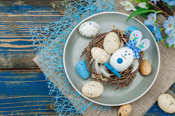 Easter table setting with eggs, bird's nest and blooming branch. Traditional festive symbols