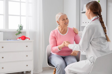 Fototapeta premium Mature woman with gynecologist holding hands in clinic. Menopause concept