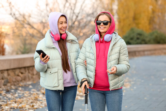 Blind young woman with her friend walking outdoors