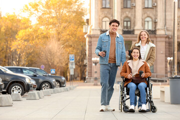 Obraz premium Young woman in wheelchair and her friends with coffee on city square