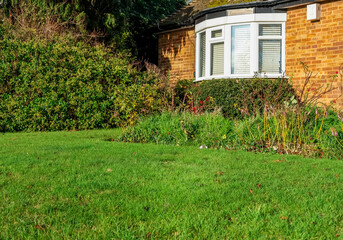 Residential brick house in Hemel Hempstead, England, featuring a bay window, green lawn, and garden area