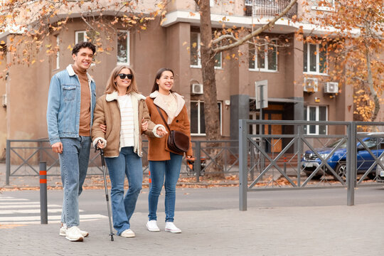 Blind young woman with her friends crossing road in city
