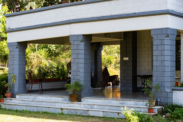 Shaded Veranda of Heritage Bungalow with Grey Pillars and Greenery