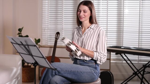 Woman playing tambourine at home. Musical instrument