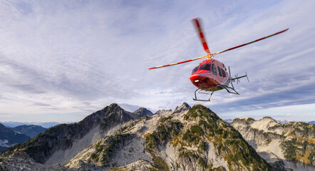 Red Helicopter Hovering Above Jagged Mountain Ridge in Clear Sky Over BC Canada © edb3_16
