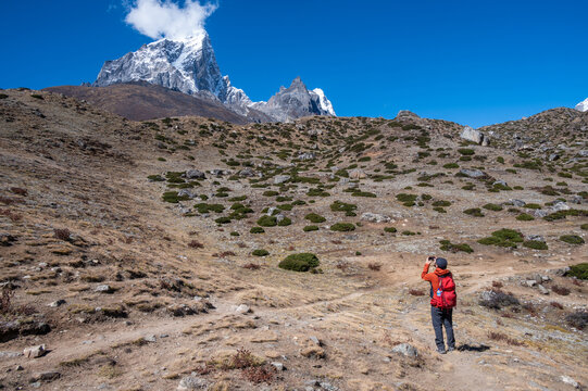 Tourist take a photograph of snowcapped mountains on the way to Dingboche village, Nepal.