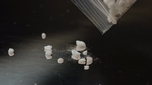 Synthetic opioid crystals like fentanyl or nitazenes drugs in clear plastic bag held in hands of drug user concept.