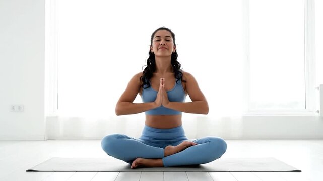 Young woman meditating in lotus pose, practicing yoga for mental and physical well-being.
