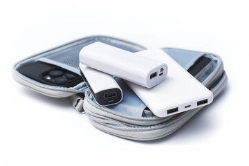 Compact white portable power banks neatly arranged inside an open gray travel organizer pouch next to a smartphone in clear case.