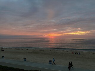 Silhouettes of people walking on the beach at sunset.