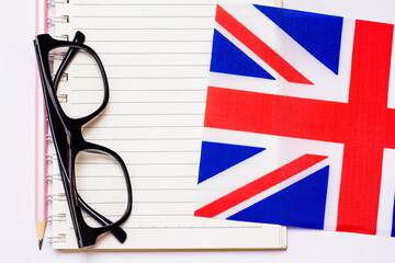 The concept of learning English includes the British flag and a notebook on a white background.