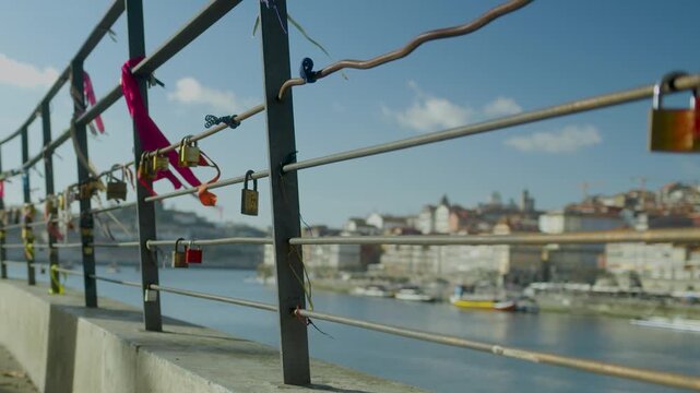Love locks attached to a bridge railing with city view in the background.