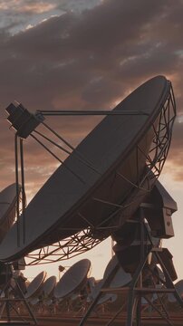 A field of large satellite dishes under a dramatic, cloudy sky with warm sunset hues