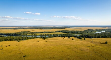 A vast, golden-yellow meadow stretches out towards a distant horizon, dotted with scattered trees and a winding river.