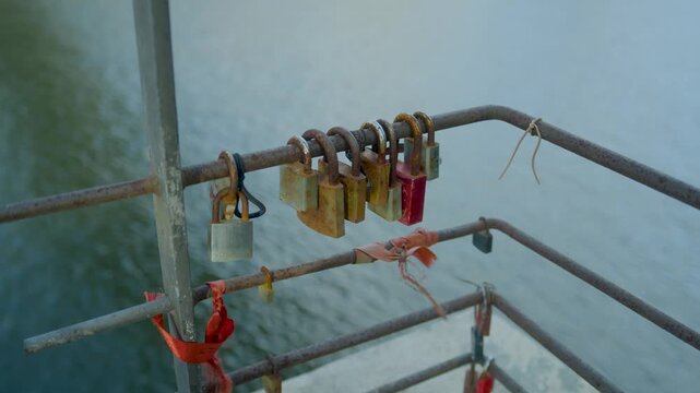 Padlocks and hanging objects attached to a bridge railing in Porto. Close-up of colorful love locks attached to a metal fence in an urban setting.