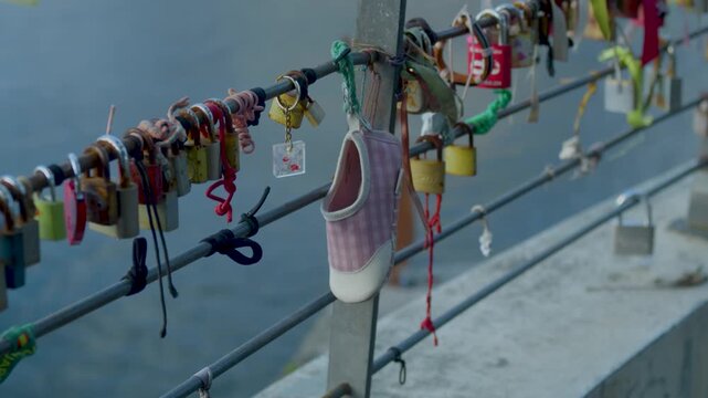 Padlocks and hanging objects attached to a bridge railing in Porto. Love locks attached to a bridge railing with city view in the background.