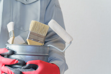 刷毛やローラーの入ったバケツを持つ作業服の人｜リフォーム・塗装業者・DIY　イメージ