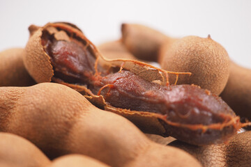 Tamarind fruit with shells and pulp on a plain background