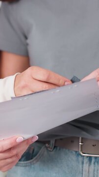 hands flipping grey sample binder pages, studio meeting closeup, woman hands examining edge and tab details, removing pinned sample for inspection, careful color and finish check during quality