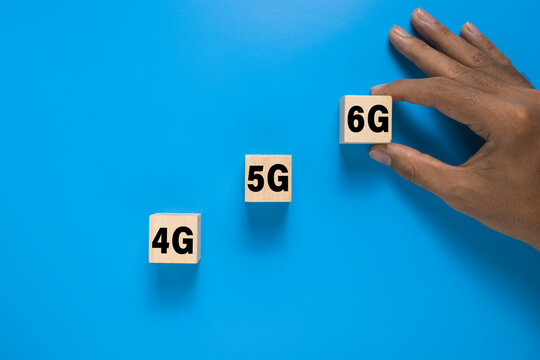 male hand put 4g, 5g, and 6g symbol on wooden blocks. isolated on blue background. concept of wireless telecommunication evolution technology - Powered by Adobe