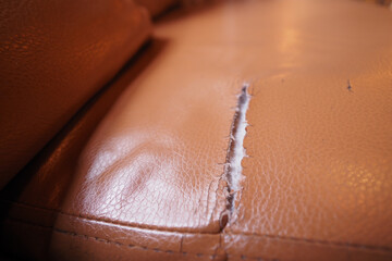 Rip on leather couch shows wear and tear over time