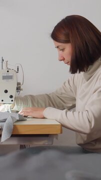 white woman finishing hem on garment meticulous hemming and pressing at industrial machine, labeling and tidying seam, calm confident maker completing handcrafted clothing, quality check