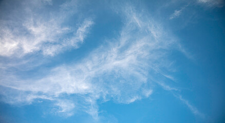 Landscape shot of a bright azure sky filled with delicate, streaky white clouds. This serene and airy image is perfect for nature backgrounds, weather themes, and peaceful designs. panolama view