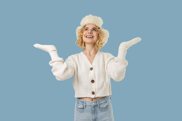 Woman in winter hat smiles against a blue background