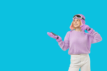 Woman wearing purple sweater and ski gear holds a phone