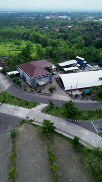 An aerial view of the PDAM Ampera building in Boyolali, featuring a spacious roundabout with a central monument, green landscaping, smooth roads, and surrounding urban greenery under a bright sky.
