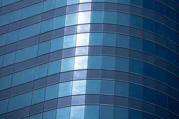 A section of a modern building with many rectangular glass windows reflecting the clear