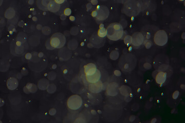 Defocused bokeh lights in various sizes and colors on a dark background creating a dreamy and abstract visual effect
