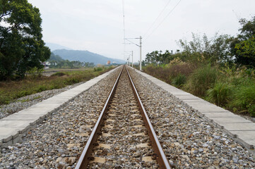Obraz premium Perspective view of a straight railway track stretching toward the horizon in a rural landscape.